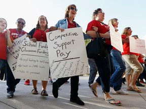 FILE--In this April 11, 2018, file photo, teachers at Tuscano Elementary School stage a "walk-in" for higher pay and school funding Wednesday, April 11, 2018, in Phoenix. Arizona teachers have voted to walk off the job to demand increased school funding, marking a key step toward a first-ever statewide strike that builds on a movement for higher pay in other Republican-dominant states.