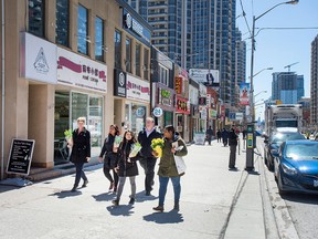 Pedestrians take flowers to a makeshift memorial at Yonge Street and Finch Avenue on April 26, 2018, in the wake of the van attack there two days previous.