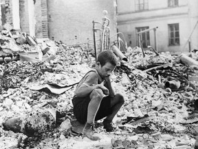 This Sept. 1939  file photo shows a young Polish boy returning to what was his home and squatting among the ruins during a pause in the German air raids on Warsaw, Poland.