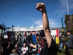 A protester raises his fist as others block a gate outside Kinder Morgan in Burnaby, B.C. on March 17, 2018.