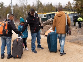 A family, claiming to be from Colombia, gets set to cross the border into Quebec from the United States as asylum seekers on April 18, 2018, near Champlain, N.Y.