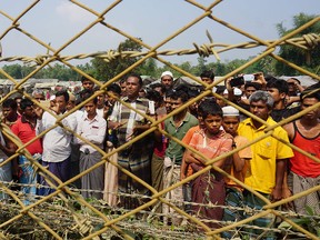 Rohingya Muslims gather behind a barbed wire fence in Maungdaw district, Rakhine State, on Myanmar's border with Bangladesh on March 18, 2018.