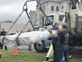 Workers use a crane as they begin installing a Ten Commandments monument outside the Arkansas state Capitol in Little Rock, Ark., Thursday, April 26, 2018. Last June, the original monument was on display for less than 24 hours before it was demolished when a man crashed his car into the original display.