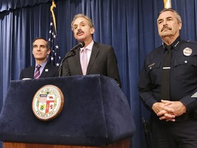 Los Angeles City Attorney Mike Feuer, middle, is flanked by Police Chief Charlie Beck, right, and Mayor Eric Garcetti during a press conference in Los Angeles Thursday, April 12, 2018. A federal judge in Los Angeles has issued a nationwide injunction barring the Justice Department from awarding priority consideration for a community policing grant if they agreed to cooperate with immigration officials. Feuer said the ruling was a "complete victory."