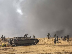 Israeli soldiers stand as smoke rises during demonstrations at the Israel Gaza border, Friday, April 6, 2018. Palestinians torched piles of tires near Gaza's border with Israel on Friday, sending huge plumes of black smoke into the air and drawing Israeli fire that killed two men in the second mass protest in the volatile area in a week.