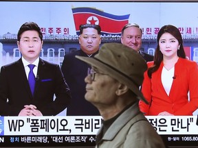A man passes by a TV screen showing file footage of CIA Director Mike Pompeo, center right, and North Korean leader Kim Jong Un, center left, during a news program at the Seoul Railway Station in Seoul, South Korea, Wednesday, April 18, 2018. Pompeo recently traveled to North Korea to meet with leader Kim Jong Un, a highly unusual, secret visit undertaken as the enemy nations prepare for a meeting between President Donald Trump and North Korean leader Kim Jong Un. The signs read: " Mike Pompeo meets with Kim Jong Un."