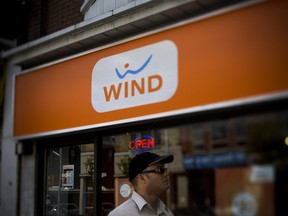 A man walks in front of a Wind Mobile SA store in Toronto on Saturday, Aug. 3, 2013.