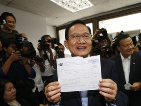 Thailand's former Prime Minister Somchai Wongsawat shows receipt after registering his membership to Pheu Thai Party in Bangkok, Thailand, Wednesday, April 4, 2018. Pheu Thai members, representing the legacy of former Prime Minister Thaksin Shinawatra, the party's guiding light, signed up Wednesday at its headquarters.