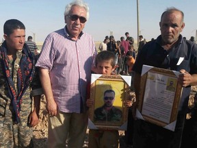 This June 28, 2017 provided by Omar Alloush, show Alloush, a senior Kurdish official, center, standing next to family members of a fighter from the Syrian Democratic Forces who was killed in battle against the the Islamic State group, in Raqqa, northern Syria.