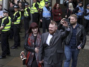 Mark Meechan gestures as he leaves Airdrie Sheriff Court in Scotland where he appeared for sentencing after he was found guilty of an offence under the Communications Act for posting a video of a dog giving Nazi salutes, Monday April 23, 2018. Meechan said the stunt was meant as a joke, but he was convicted last month of posting "grossly offensive" material. On Monday a judge ordered Meechan to pay an 800 pound ($1,200) fine.