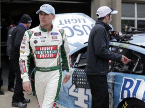 Kevin Harvick walks through the garage area as members of his team make adjustments to his car after a practice session for a NASCAR Cup series auto race in Fort Worth, Texas, Saturday, April 6, 2018.