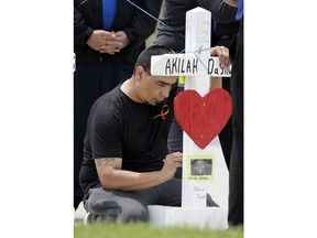 Joe Perez Sr., of Austin, Texas, writes a message on a wooden cross memorial for shooting victim Akilah DaSilva at a Waffle House restaurant Wednesday, April 25, 2018, in Nashville, Tenn. Perez's son, Joe Perez Jr., was one of four victims killed at the restaurant by a gunman Sunday. The restaurant re-opened Wednesday and the company intends to donate its first month of sales to help victims of the attack.