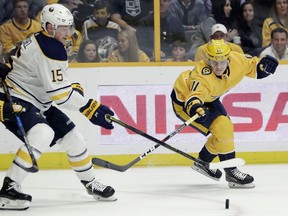 Buffalo Sabres center Jack Eichel (15) and Nashville Predators right wing Eeli Tolvanen (11), of Finland, reach for the puck in the first period of an NHL hockey game Saturday, March 31, 2018, in Nashville, Tenn.