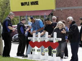 Family members of people killed at a Waffle House restaurant write messages on wooden crosses set up as a memorial Wednesday, April 25, 2018, in Nashville, Tenn. Four people were killed when a gunman opened fire at the restaurant Sunday. Members of the Waffle House management and staff joined the family members as the restaurant re-opened Wednesday.