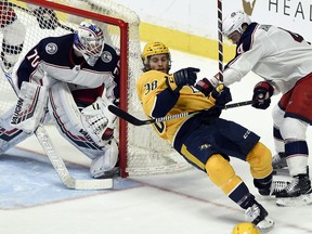 Columbus Blue Jackets defenseman Scott Harrington (4) checks Nashville Predators right wing Ryan Hartman (38) in front of Blue Jackets' goaltender Joonas Korpisalo (70), of Finland, during the first period of an NHL hockey game Saturday, April 7, 2018, in Nashville, Tenn.