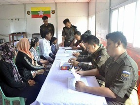 In this April 14, 2018, photo provided by  Myanmar Government Information Committee,  Myanmar immigration officials examine documents as a Rohingya family of five look on at a receiving center in Taung Pyo, Letwe, northern Rakhine state.  Myanmar has accepted what appears to be the first five among some 700,000 Rohingya Muslim refugees who fled military-led violence against the minority group, even though the U.N. says it is not yet safe for them to return home. (Myanmar Government Information Committee via AP)