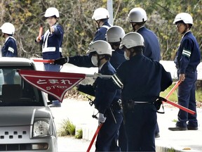 In this April 11, 2018, photo, police officers inspect cars at a checkpoint in Onomichi, Hiroshima prefecture. Japanese police have deployed hundreds of policemen in pursuit of a jail breaker who landed on a tiny island near Hiroshima with abundant hideouts, some 1,000 vacant homes left behind as the island population aged and shrunk. The 27-year-old Tatsuma Hirao has been at large since Sunday, April 8 when he fled from a prison in Ehime prefecture where he was serving his term for his convicted theft.