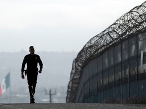 In this June 22, 2016 file photo, Border Patrol agent Eduardo Olmos walks near the secondary fence separating Tijuana, Mexico and San Diego.