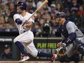 Houston Astros' Jose Altuve, left, hits a double during the first inning of a baseball game against the San Diego Padres, Saturday, April 7, 2018, in Houston.