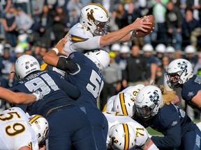 FILE - In this Oct. 14, 2017, file photo, Wyoming quarterback Josh Allen leaps over Utah State defensive end Devon Anderson (91) and linebacker Justus Te'i (51) to score a touchdown during an NCAA football game in Logan, Utah. Allen is expected to be a first round pick in the NFL Draft.