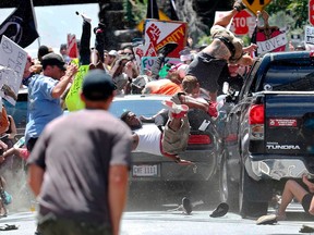 In this Aug. 12, 2017, photo by Ryan Kelly of The Daily Progress, people fly into the air as a car drives into a group of protesters demonstrating against a white nationalist rally in Charlottesville, Va.