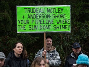 A man holds a sign while listening as other protesters opposed to the Kinder Morgan Trans Mountain pipeline extension defy a court order and block an entrance to the company's property, in Burnaby, B.C., on Saturday April 7, 2018. The pipeline is set to increase the capacity of oil products flowing from Alberta to the B.C. coast to 890,000 barrels from 300,000 barrels.
