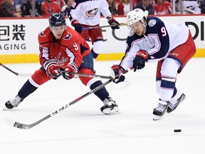 Washington Capitals defenseman Dmitry Orlov, left, of Russia, fights for the puck against Columbus Blue Jackets left wing Artemi Panarin, of Russia, during the second period in Game 1 of an NHL first-round hockey playoff series Thursday, April 12, 2018, in Washington.