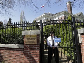 As a Russian flag continues to fly from the roof, a security official stands just inside the gate to the former Russian consul general's residence Wednesday, April 25, 2018, in Seattle. Officials with the U.S. State Department have drilled out locks to access and inspect the home, a day after Russian staff vacated the site. President Donald Trump's administration announced last month that the diplomatic outpost would be closed and 60 Russian diplomats would be expelled nationwide to punish Moscow for its alleged role in poisoning an ex-spy in Britain.