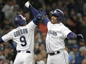 Seattle Mariners' Jean Segura, right, is cheered by Dee Gordon (9) after hitting a three-run home run against the Oakland Athletics in the second inning during a baseball game Saturday, April 14, 2018, in Seattle.