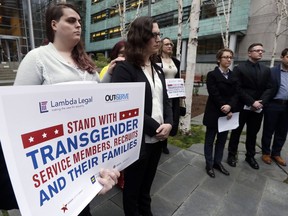 FILE - In this March 27, 2018, file photo, plaintiffs Cathrine Schmid, second left, and Conner Callahan, second right, listens with supporters during a news conference in front of a federal courthouse following a hearing in Seattle. A federal judge in Seattle has ordered President Donald Trump not to take any action barring transgender troops from serving in the military, finding that it's unclear whether recent tweaks to his administration's policy are constitutional. In an order Friday, April 13, 2018, U.S. District Judge Marsha Pechman said that because the tweaks were announced just last month, the parties had not had time to argue about whether the policy is unconstitutionally discriminatory or whether the military is entitled to deference.