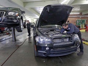 In this Wednesday, April 25, 2018, photo, auto technician Anthony Sterns, right, works to replace the coolant expansion tank on a 2011 BMW at the Fat City German Car service shop in Seattle. At first, dumping your old car might seem like a no-brainer, and you can't help picturing how good you would look in that new car. But automotive experts say you'll almost always come out ahead, at least financially, by fixing old faithful.