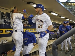 Milwaukee Brewers' Travis Shaw (21) celebrates his two-run home run against Chicago Cubs starting pitcher Kyle Hendricks with teammate Orlando Arcia in the dugout during the fifth inning of a baseball game Friday, April 6, 2018, in Milwaukee.