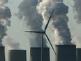 A wind turbine spins amidst exhaust plumes from cooling towers at a coal-fired power station in Jaenschwalde, Germany.