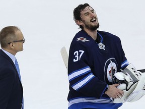Winnipeg Jets goaltender Connor Hellebuyck (right) shares a laugh with head coach Paul Maurice after the Jets beat the Minnesota Wild in their first-round playoff series on April 20.