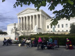 In this April 23, 2018, photo, people wait in line outside the Supreme Court in Washington, to be in the gallery when the court hears arguments in on April 25, over President Donald Trump's ban on travelers from several mostly Muslim countries.