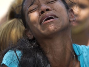 A relative grieves during the funeral of Alirio Duran, 25, at the Municipal Cemetery of Valencia, Venezuela, Friday, March 30, 2018. Weeping relatives arrived at the central cemetery on Friday carrying the caskets of many of the 68 victims who were killed in a police station fire to place them in a freshly dug mass tomb. Cemetery workers said they were prepared to bury at least 32 people two days after the blaze in three-deep graves separated by a layer of cinderblock.