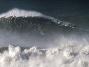 In this photo taken Nov. 8 2017, Brazilian surfer Rodrigo Koxa rides what has been judged the biggest wave ever surfed, at the Praia do Norte, or North beach, in Nazare, Portugal.