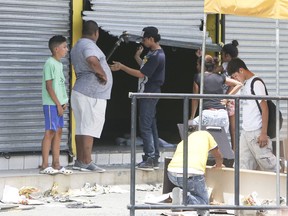 People stand in front of a store that has just been forced open and looted, in Managua, Nicaragua, Sunday, April 22, 2018. Dozens of shops in the Nicaraguan capital have been looted in the continuation of protests and disturbances sparked by government social security reforms.