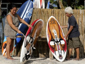 Filipinos clean surfboards outside their closed shop as the government implements the temporary closure of the country's most famous beach resort island of Boracay, in central Aklan province, Philippines, Thursday, April 26, 2018. Boracay, famed for its white-sand beaches, closes for up to six months to recover from overcrowding and development.