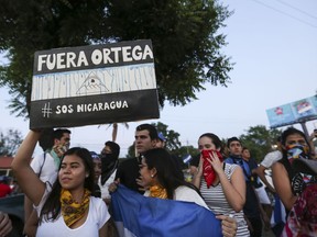 A woman holds a sign that reads in Spanish "Ortega Out," during a protest against the government of President Daniel Ortega, in Managua, Nicaragua, Sunday, April 11, 2018. President Ortega has withdrawn changes to the social security system that touched off protests across the Central American nation that escalated into clashes with police leaving dozens dead.