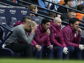 Manchester City coach Pep Guardiola, left, on the bench during the English Premier League soccer match between Manchester City and Manchester United at the Etihad Stadium in Manchester, England, Saturday April 7, 2018.