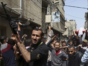 Relatives carry the body of Mohammed Hajeleh, 30, who was killed early Thursday morning by an Israeli airstrike, while others fire their weapons in the air, during his funeral, in front of his family house in Gaza City, Thursday, April 12, 2018.