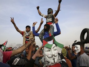 Palestinian masked protesters chants slogans in front of the Gaza's border with Israel, east of Khan Younis, Gaza Strip, Thursday, April 5, 2018. An Israeli airstrike in northern Gaza early on Thursday killed a Palestinian, while a second man died from wounds sustained in last week's mass protest. The fatalities bring to 21 the number of people killed in confrontations in the volatile area over the past week with a new round of protests along the border is expected on Friday.