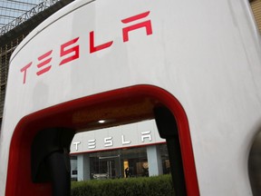 A sales person stands inside a Tesla electric vehicle showroom in Beijing, Thursday, April 5, 2018. The United States and China, the world's two largest economies, have roiled financial markets and fueled fears of a protracted trade war by threatening tariffs this week on each other's goods. The United States on Tuesday said it would impose 25 percent duties on $50 billion of imports from China, and China quickly retaliated by listing $50 billion of products that it could hit with its own 25 percent tariffs.