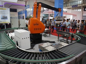 In this Aug. 23, 2017, photo, visitors watch a Chinese-made industrial robot demonstrating on lifting goods during the World Robot Conference at the Yichuang International Conference and Exhibition Centre in Beijing. China On Wednesday, April 4, 2018 vowed to take measures of the "same strength" in response to a proposed U.S. tariff hike on $50 billion worth of Chinese goods in a spiraling dispute over technology policy that has fueled fears it might set back a global economic recovery. The Commerce Ministry said it would immediately challenge the U.S. move in the World Trade Organization.