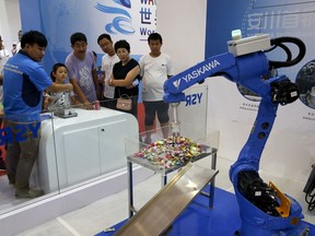 In this Aug. 23, 2017, photo, an exhibitor demonstrates a Chinese-made industrial robot to visitors at the World Robot Conference at the Yichuang International Conference and Exhibition Centre in Beijing. China On Wednesday, April 4, 2018 vowed to take measures of the "same strength" in response to a proposed U.S. tariff hike on $50 billion worth of Chinese goods in a spiraling dispute over technology policy that has fueled fears it might set back a global economic recovery. The Commerce Ministry said it would immediately challenge the U.S. move in the World Trade Organization.