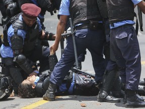 Riot police tend to a fellow officer who was wounded in the leg after a homemade mortar fired by protesters struck her, in Managua, Nicaragua, Friday, April 20, 2018. Police in Nicaragua say that a police officer, protester, and pro-government activist have been killed so far in clashes sparked over a planned social security reform.