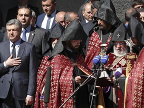 Armenian acting Prime Minister Karen Karapetian, left, and Armenian Apostolic Church leader Catholicos Garegin II, second right, attend a memorial service at the monument to the victims of mass killings by Ottoman Turks, to commemorate the 103rd anniversary of the massacre in Yerevan, Armenia, Tuesday, April 24, 2018. Tuesday's commemoration of the massacre that began 103 years ago --viewed by Armenians and many historians as genocide -- comes after the country's prime minister resigned in a surprise move following days of anti-government protests.