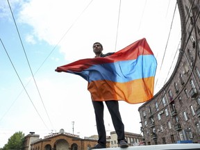 A demonstrator waves an Armenian national flag during a protest against the appointment of former President Serzh Sargsyan as the new prime minister, in Yerevan, Armenia, Sunday, April 22, 2018. Crowds of protesters gathered in various districts of Yerevan and there were clashes as police tried to break them up, with some scores of demonstrators detained Sunday, said police spokesman Ashot Aragonian.