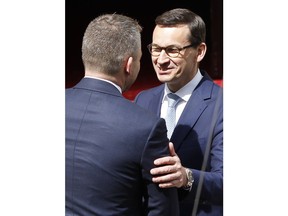 Polish Prime Minister Mateusz Morawiecki, right, welcomes  Prime Minister of Slovakia Peter Pellegrini, left, during a ceremony before a meeting in Warsaw, Poland, Wednesday, April 25, 2018.